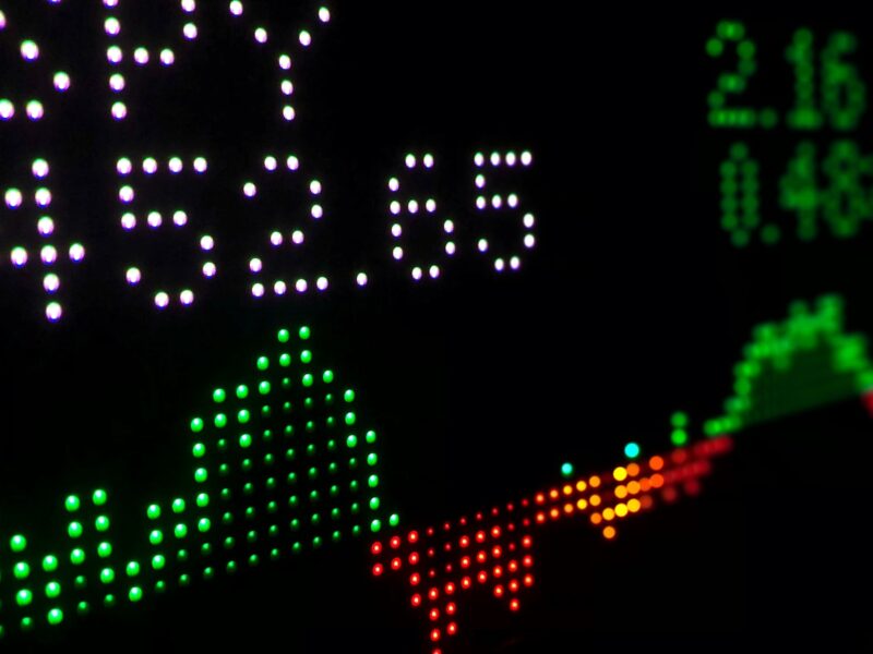 AI-generated illustration of a financial trading floor with cryptocurrency charts showing downward trends in blue and red lighting