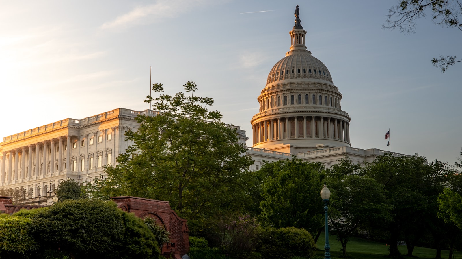 AI-generated illustration of the US Capitol building at dusk with a data center and courthouse in split foreground, representing the federal vs state AI regulation debate