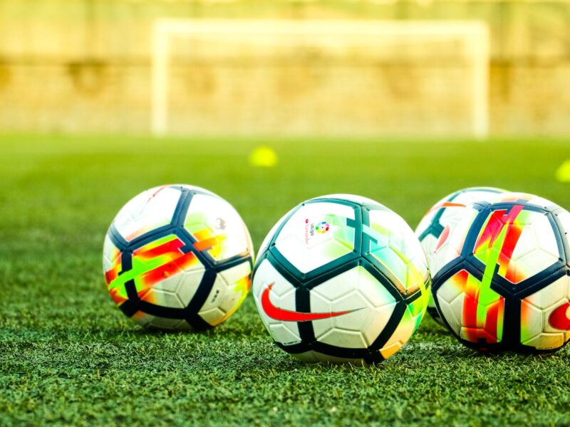 AI-generated illustration of two football teams facing off on a floodlit pitch at dusk, with tactical formation lines visible on the turf