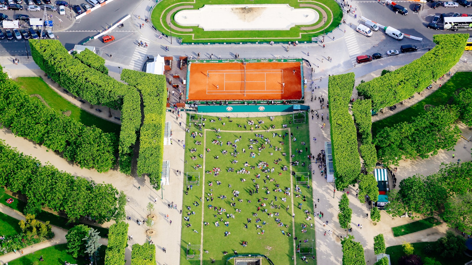 AI-generated aerial illustration of the All England Club's Centre Court surrounded by manicured grass courts on a bright summer day, Wimbledon tournament atmosphere