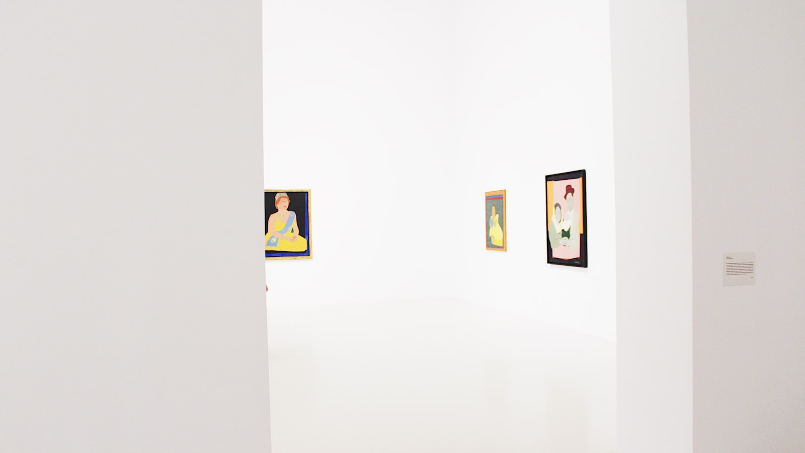 An empty gallery room with framed artworks hung on white walls above a polished floor under soft even lighting