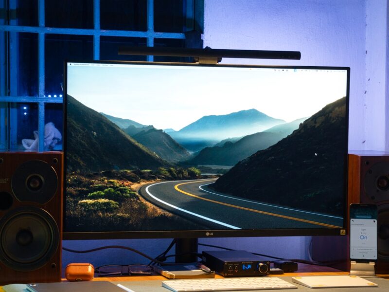 AI-generated illustration of a curved gaming monitor on a desk displaying an unwanted security software pop-up on a Windows 11 desktop, representing adware delivered via silent hardware install