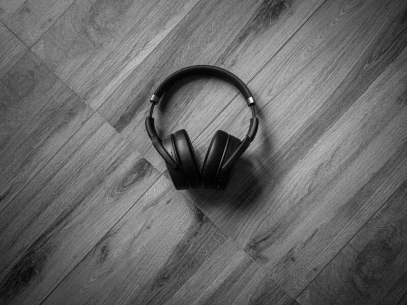 A vinyl record and headphones resting on a wooden table beside a window in warm afternoon light