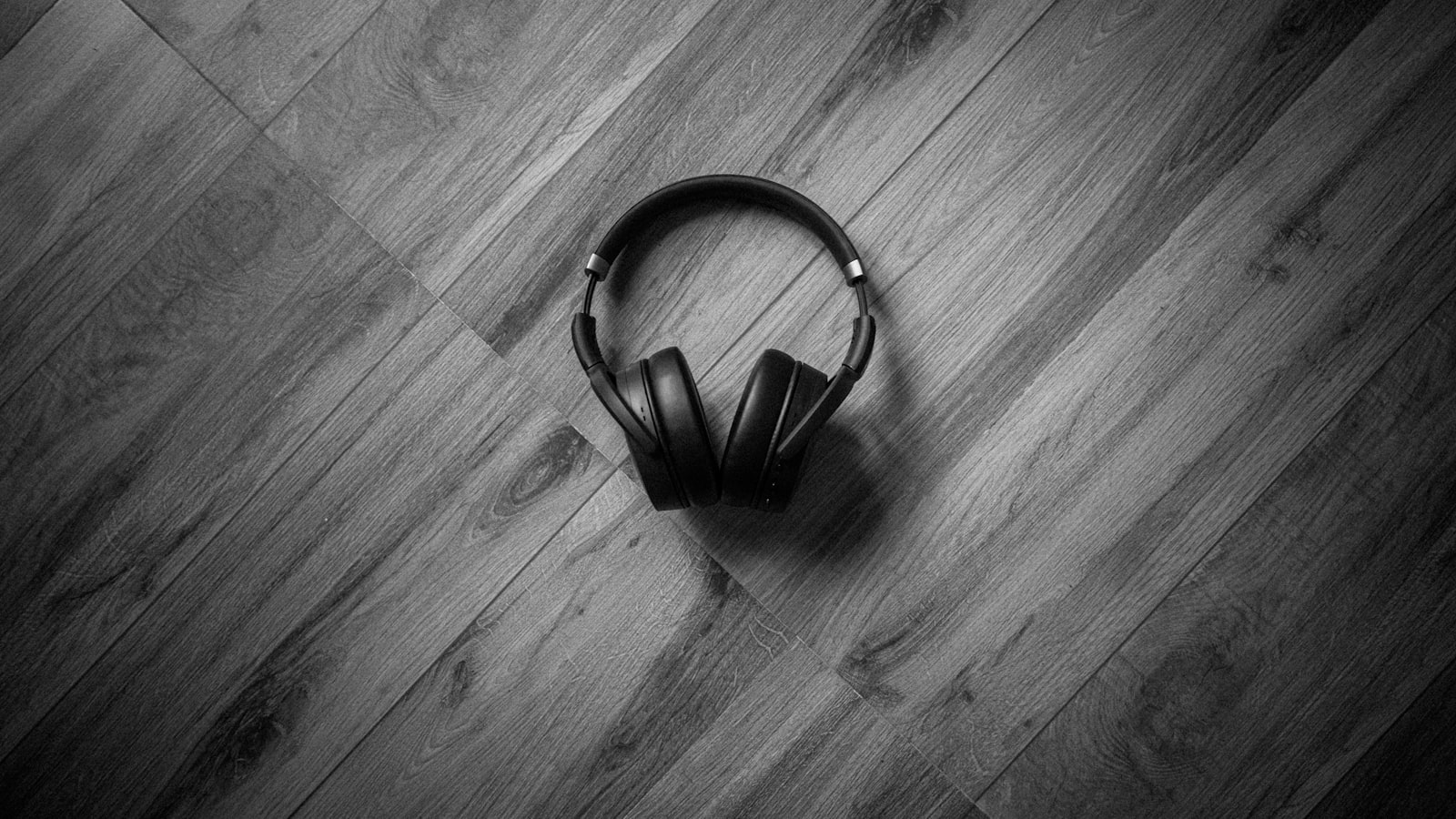 A vinyl record and headphones resting on a wooden table beside a window in warm afternoon light