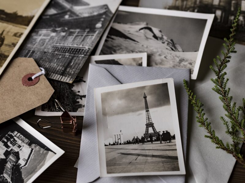 Old family photographs and strips of negatives laid out on a table beside a plain storage box in soft daylight