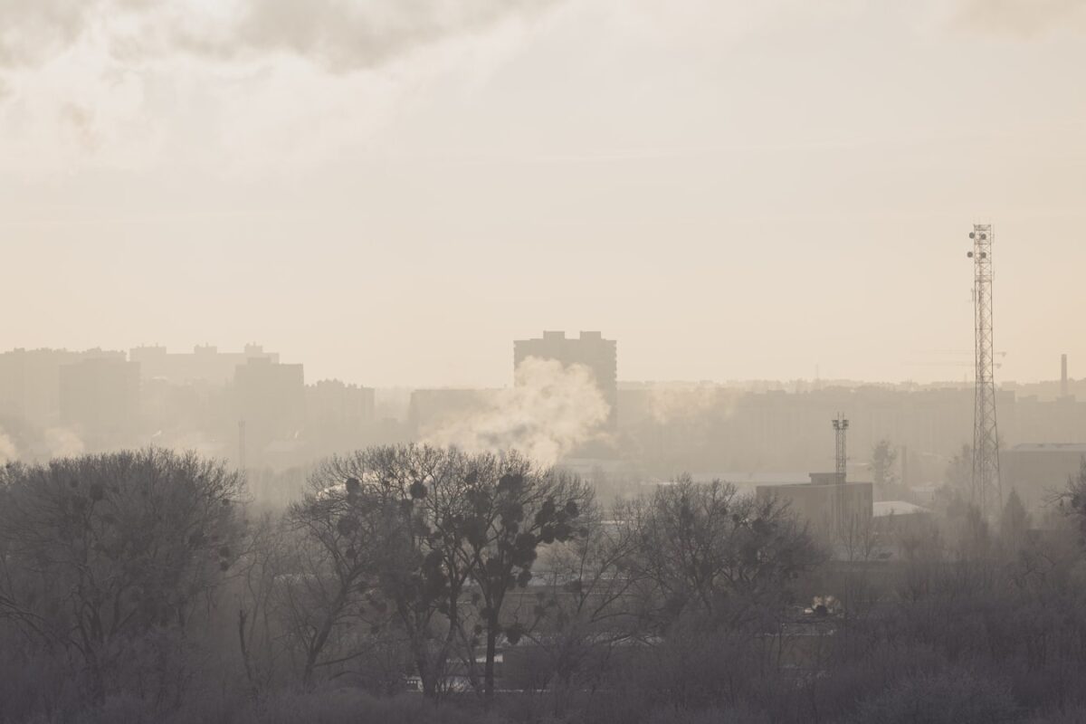 AI-generated illustration of a large warehouse complex burning with thick black smoke columns rising into a grey sky, representing drone strikes on Russian logistics infrastructure