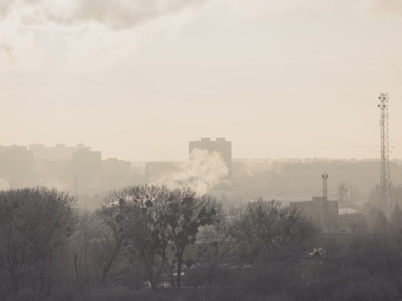 AI-generated illustration of a large warehouse complex burning with thick black smoke columns rising into a grey sky, representing drone strikes on Russian logistics infrastructure